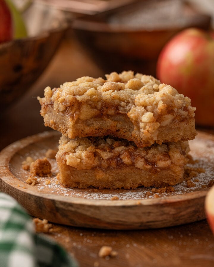 Close-up of two apple crumble bars showing chunky cinnamon apples between a brown butter crust and golden crumble topping.
